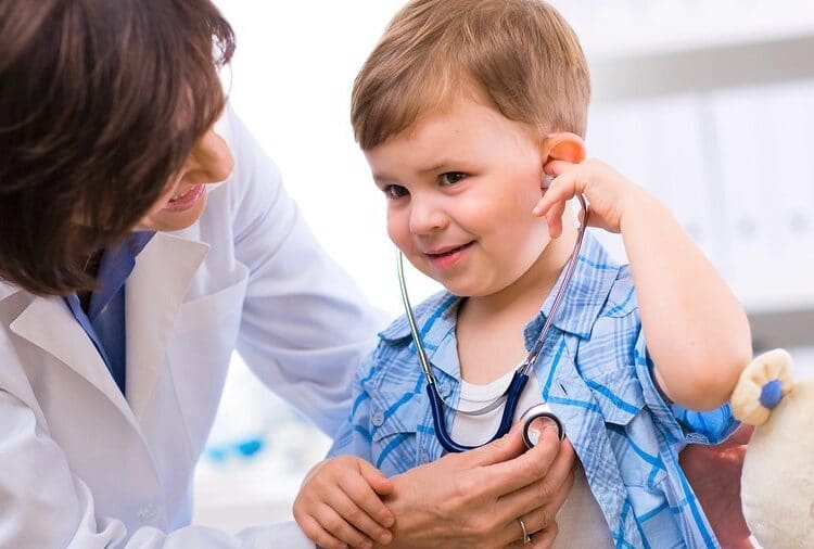 Senior female doctor examining happy child smiling.