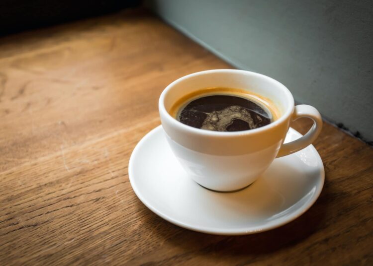 a cup of black coffee on the wooden windowsill