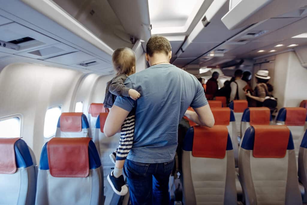 adult carrying toddler down the aisle of an airpla 2026 03 17 08 58 29 utc scaled 1