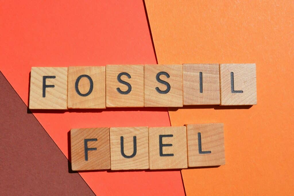 fossil fuel words in wooden alphabet letters isolated on red background