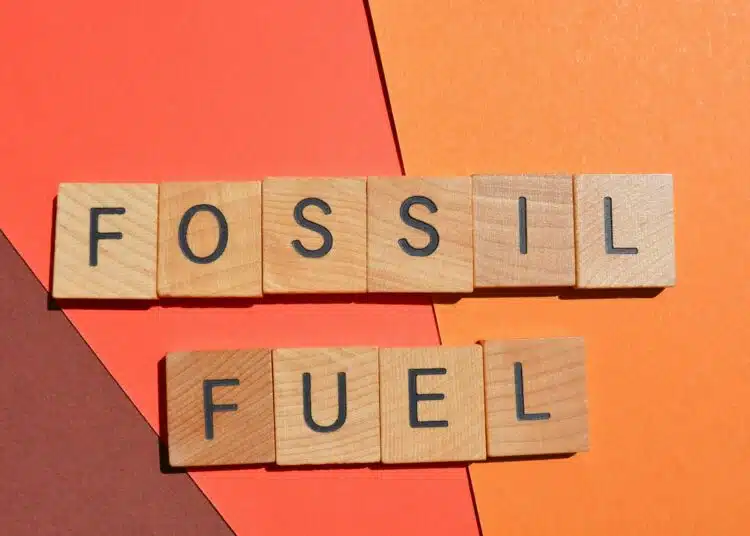 fossil fuel words in wooden alphabet letters isolated on red background