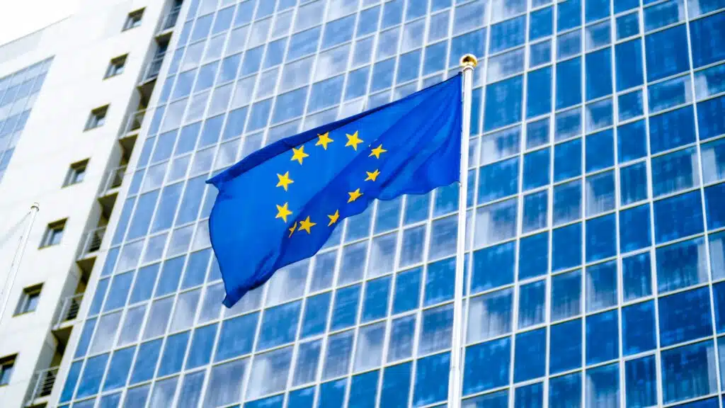ЕК прие окончателните стандарти за ESG отчитане 2 image of eu flag fluttering on wind against high business office building made of concerete and